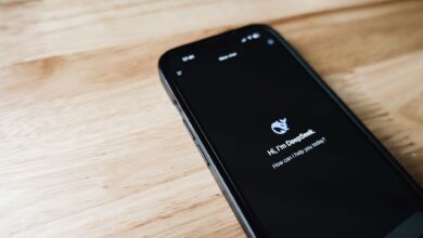 Close-up of a smartphone with DeepSeek virtual assistant on screen, placed on a wooden surface.