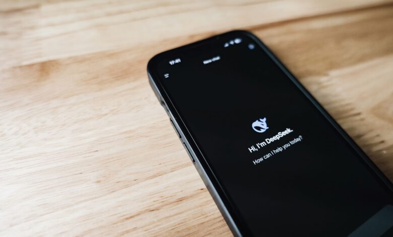 Close-up of a smartphone with DeepSeek virtual assistant on screen, placed on a wooden surface.