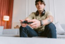 Young man focused on video gaming at home wearing headphones and a smartwatch.