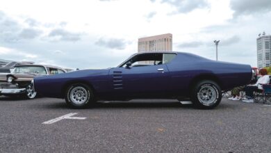 Classic muscle car parked outdoors with cityscape background. Ideal for automotive enthusiasts.