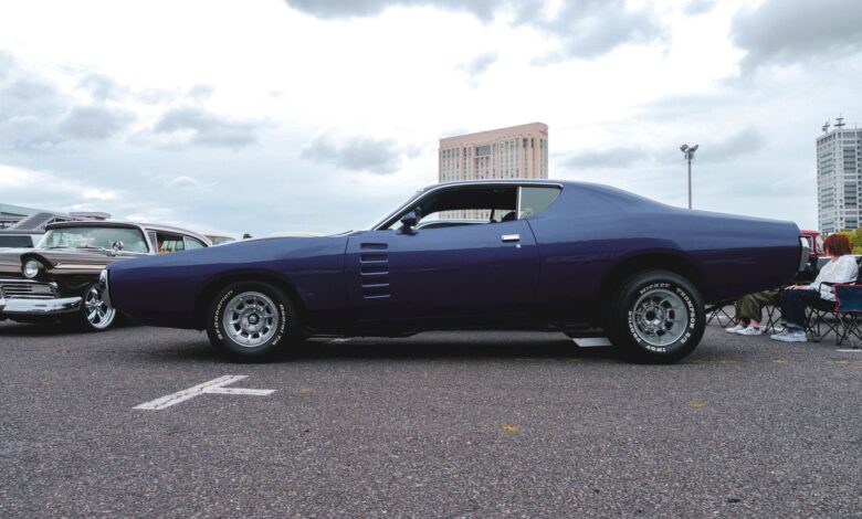 Classic muscle car parked outdoors with cityscape background. Ideal for automotive enthusiasts.