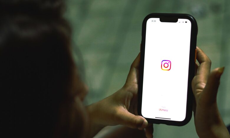 Close-up of a woman holding a smartphone displaying the Instagram app indoors.