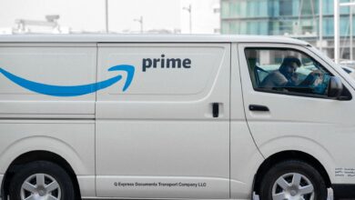 A white delivery van with Prime logo parked on an urban street with driver inside.