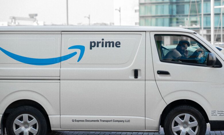 A white delivery van with Prime logo parked on an urban street with driver inside.