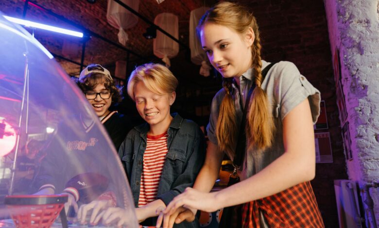 Group of teenagers having fun playing arcade games indoors.