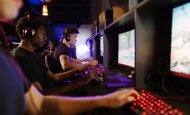 Young adults gaming at a modern LAN center with advanced PCs, showcasing intense gaming focus.