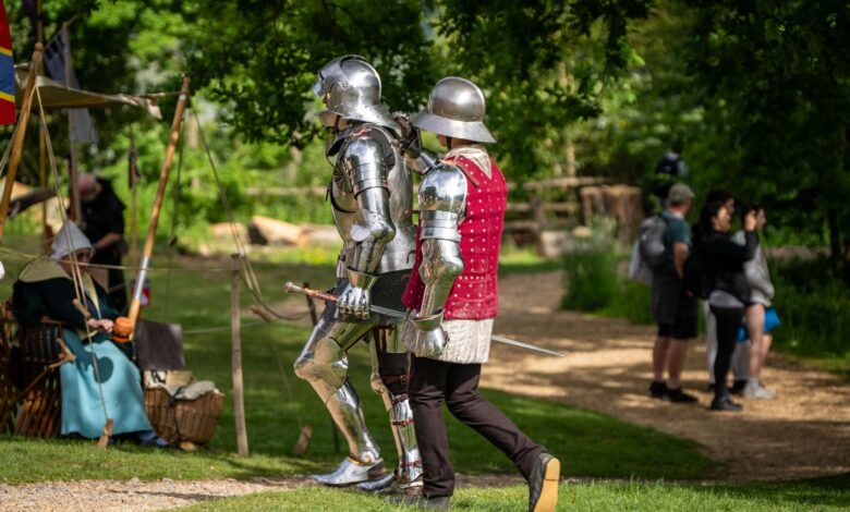 Historic re-enactment with knights in full armor at a festive outdoor event.