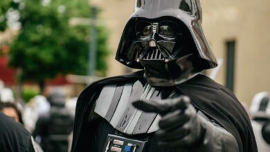 Darth Vader cosplayer pointing in an outdoor setting, showcasing detailed costume and helmet.