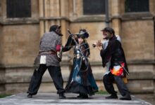 Intense cosplay battle with swords in a medieval outdoor setting.