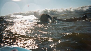 A surfer paddles through shimmering ocean waves under a glowing sunset, capturing a moment of pure adventure.