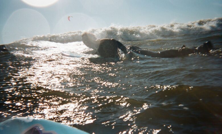 A surfer paddles through shimmering ocean waves under a glowing sunset, capturing a moment of pure adventure.