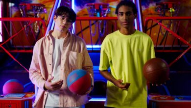 Two young men holding basketballs at an amusement arcade, engaging in a fun indoor game.