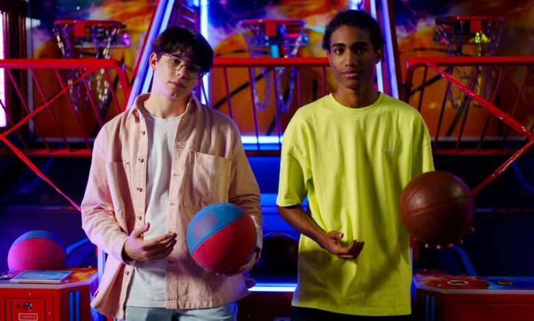 Two young men holding basketballs at an amusement arcade, engaging in a fun indoor game.