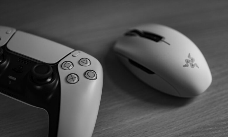 Monochrome image of a gaming controller and mouse on a desk, highlighting modern technology.