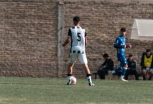 Teenage soccer player in action on the field, wearing number 5 jersey outdoors.