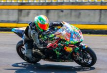 Motorcycle racer on a colorful sports bike speeding down a race track.