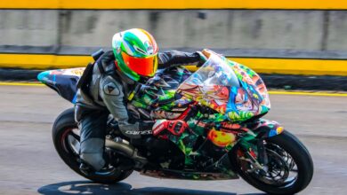Motorcycle racer on a colorful sports bike speeding down a race track.
