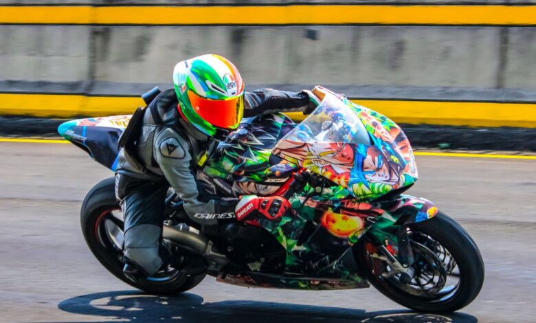 Motorcycle racer on a colorful sports bike speeding down a race track.