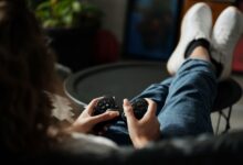 Close-up of woman gaming with a controller, feet propped up, enjoying leisure time indoors.