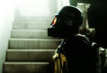 Dark indoor scene featuring a figure in gas mask and helmet, evoking horror and Halloween vibes.