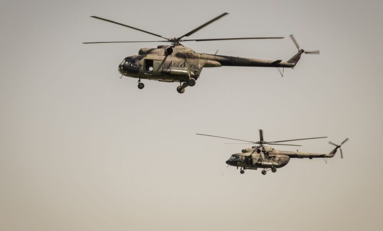 Two military helicopters flying over clear skies, showcasing aviation power.