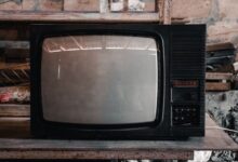 A classic black CRT television in a rustic, workshop environment with a nostalgic vibe.