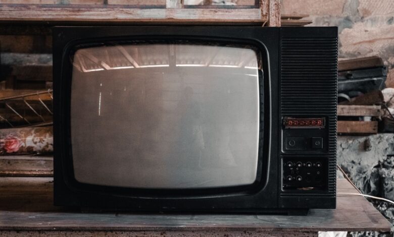 A classic black CRT television in a rustic, workshop environment with a nostalgic vibe.