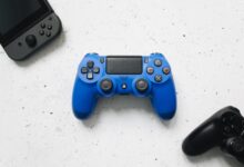 A top view of various colorful gaming controllers on a white surface.