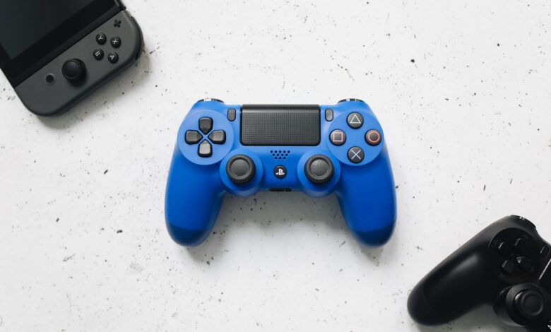 A top view of various colorful gaming controllers on a white surface.