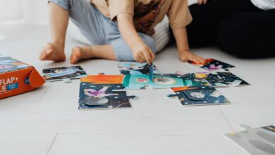 Two children assembling a colorful puzzle on the floor indoors.