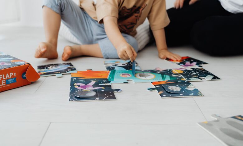 Two children assembling a colorful puzzle on the floor indoors.