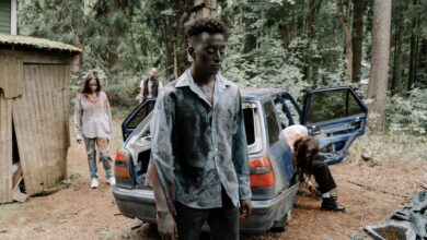 A chilling zombie scene unfolds by an abandoned car in a dense forest.