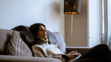 Woman wearing turtleneck relaxing with a game controller on a cozy sofa in Edinburgh living room.
