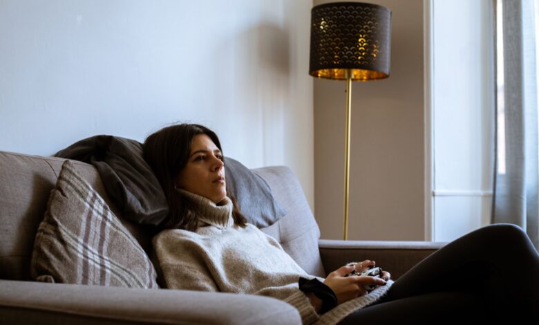 Woman wearing turtleneck relaxing with a game controller on a cozy sofa in Edinburgh living room.