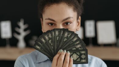 A woman with a focused expression holding a fan of tarot cards, conveying mystery and reflection.