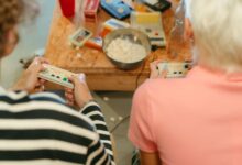 Two teenagers play video games together with snacks, creating a fun indoor atmosphere.
