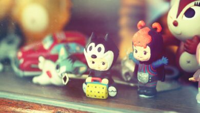Close-up of vintage toy figurines on a wooden shelf inside a glass display case.