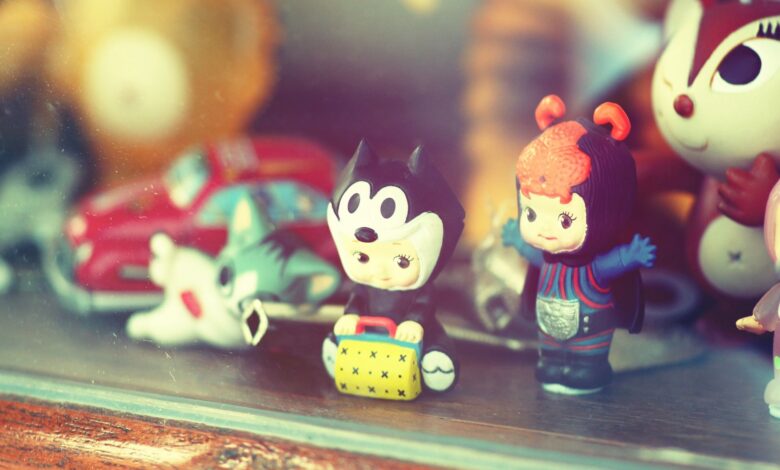 Close-up of vintage toy figurines on a wooden shelf inside a glass display case.