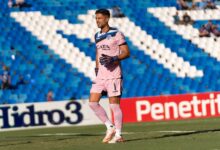 Goalkeeper wearing pink kit on the soccer field during a match.