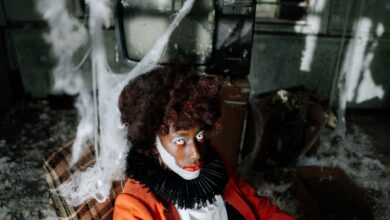 Creepy clown in an abandoned room filled with cobwebs, creating a spooky Halloween ambiance.