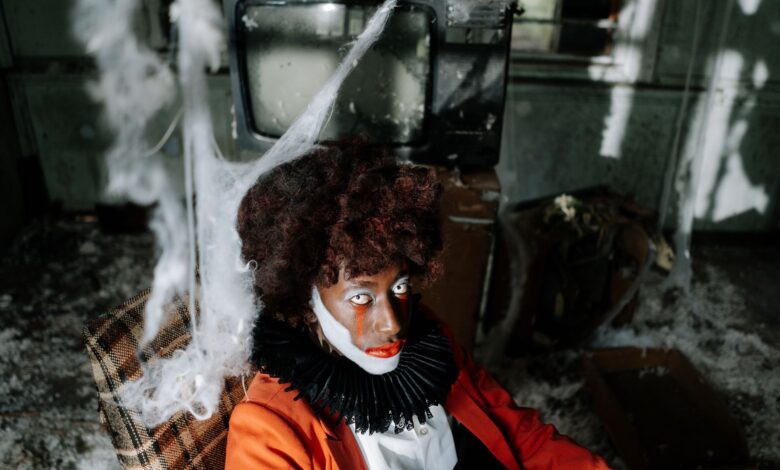 Creepy clown in an abandoned room filled with cobwebs, creating a spooky Halloween ambiance.