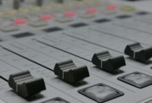 Detailed view of audio mixer sliders in a recording studio setting.