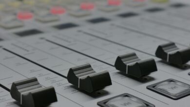 Detailed view of audio mixer sliders in a recording studio setting.