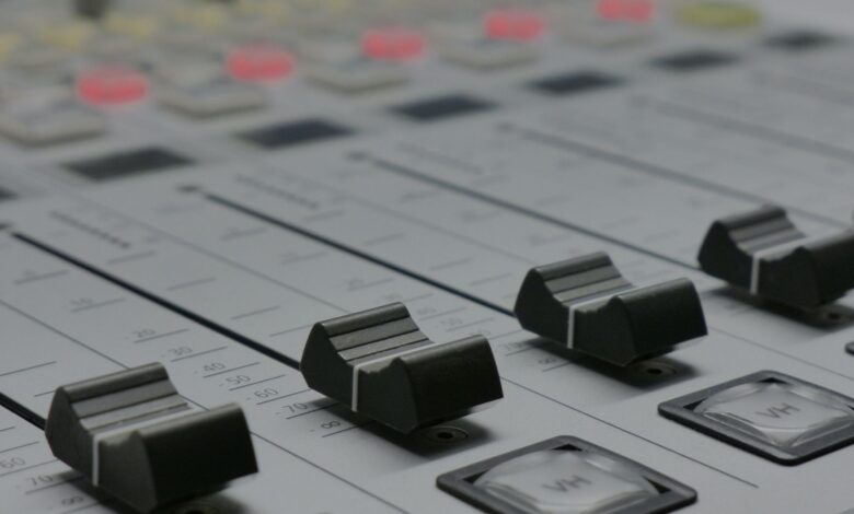 Detailed view of audio mixer sliders in a recording studio setting.