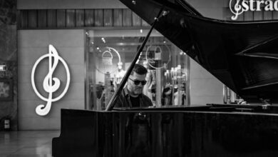 Black and white image of a man playing a grand piano indoors with musical symbols in the background.