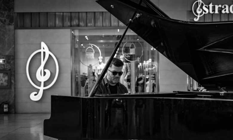 Black and white image of a man playing a grand piano indoors with musical symbols in the background.