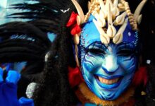 Close-up of a person in vibrant costume and blue face paint at Menton Carnival.