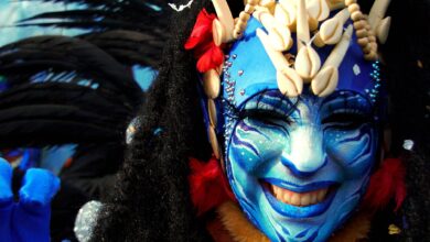 Close-up of a person in vibrant costume and blue face paint at Menton Carnival.