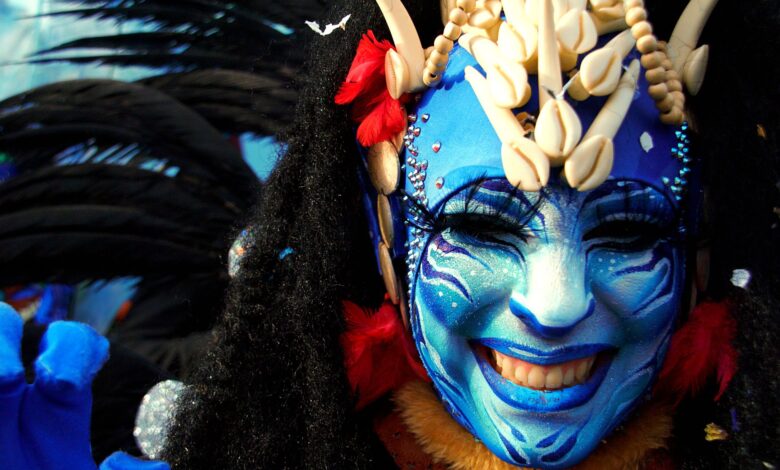 Close-up of a person in vibrant costume and blue face paint at Menton Carnival.