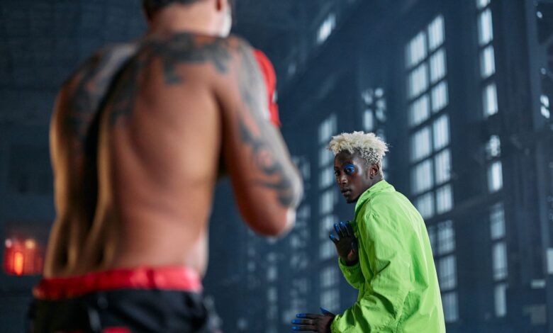 Two fighters engaged in cosplay-themed martial arts sparring inside a warehouse.